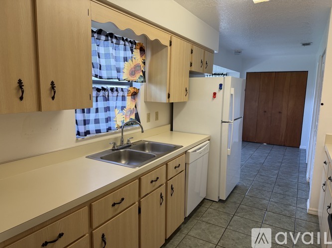 A kitchen with wooden cabinets and a checkered curtain.