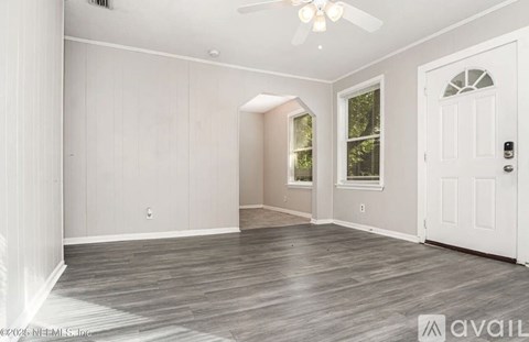 A spacious room with a white door and a ceiling fan.