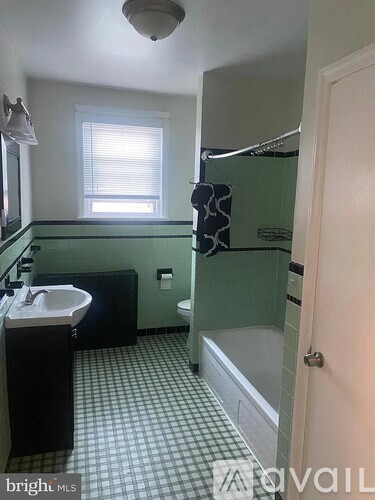 A bathroom with a green shower stall and a white sink.