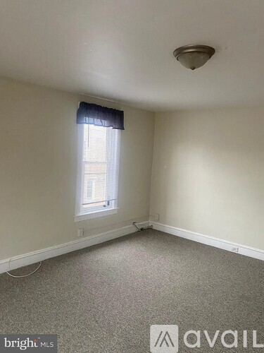 A room with a window and a carpeted floor.