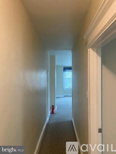 A hallway with a carpeted floor and white walls.