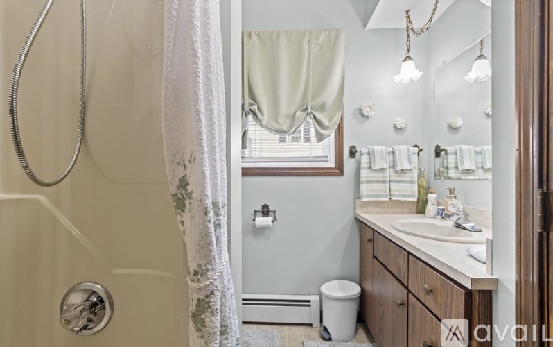 A bathroom with a shower, sink, and mirror.