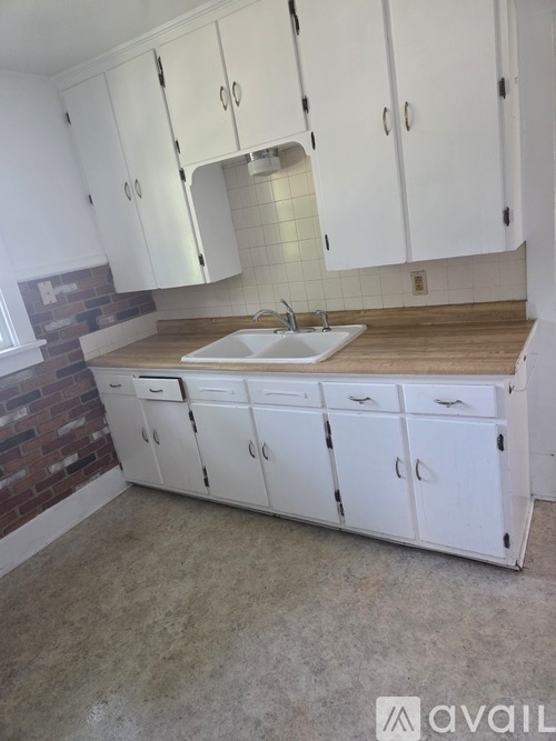 A kitchen with white cabinets and a brick wall.