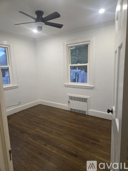 A room with a ceiling fan and a window with a view of trees.