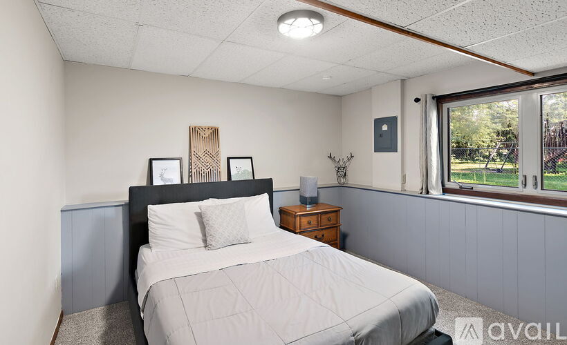 A bedroom with a large bed and a window overlooking a garden.
