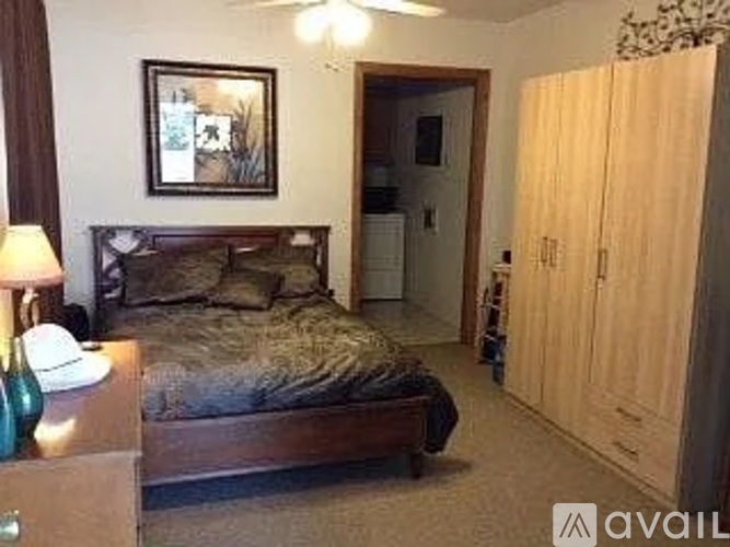 A bedroom with a bed, dresser, and a painting on the wall.