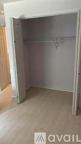 A white closet with a hanger bar and a door open.