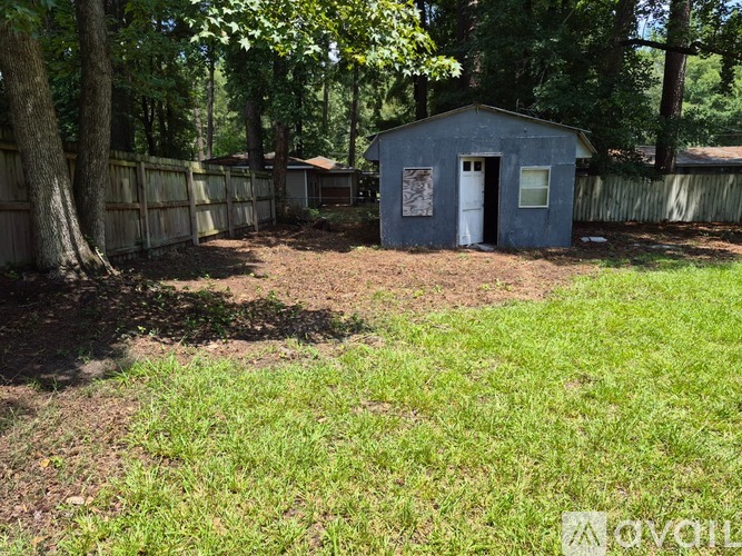 A small blue shed sits in a yard with a white door.