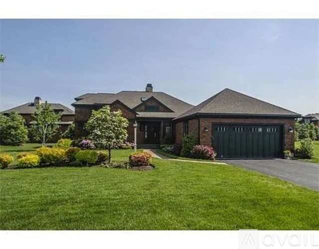 A large house with a driveway and a well-maintained lawn.