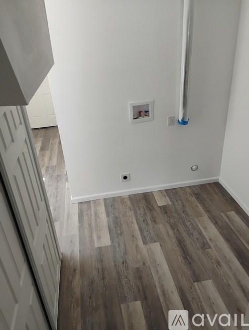 A room with a white wall and a wooden floor.