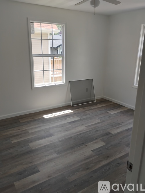 A room with a window and a laptop on the floor.