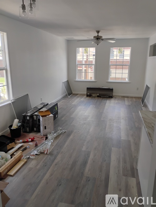 A room with wooden flooring and a ceiling fan is shown.