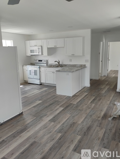A kitchen with white cabinets and a wooden floor.