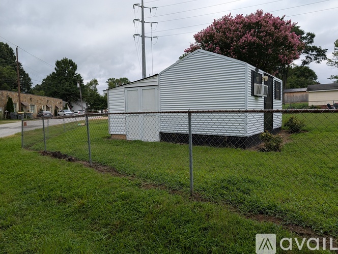 A silver metal building with a fence in front of it.