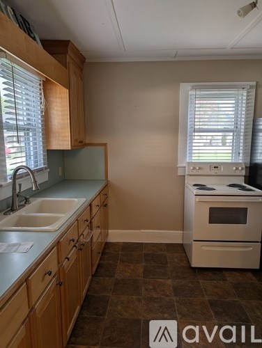 A kitchen with a white stove and wooden cabinets.