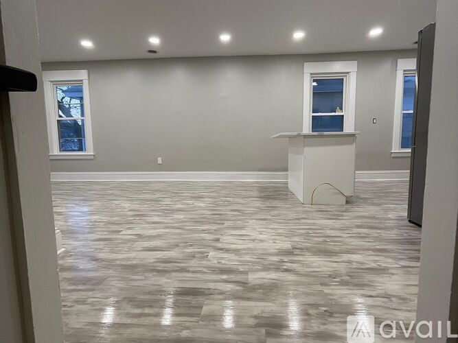 A spacious room with marble flooring and two windows.