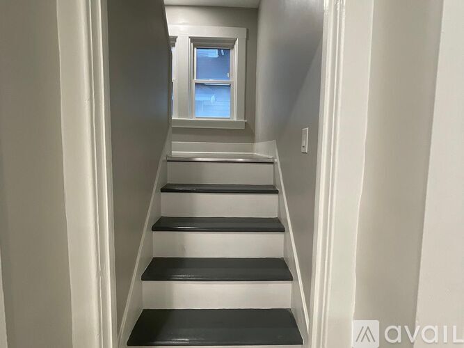 A staircase with black and white steps leading to a window.