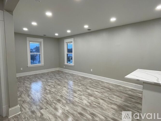 A spacious room with a marble floor and two windows.