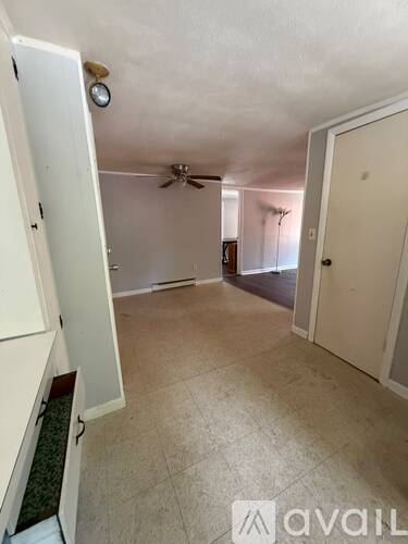 A room with a ceiling fan and a door leading to another room.