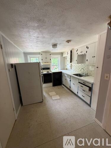 A kitchen with white cabinets and a white fridge.