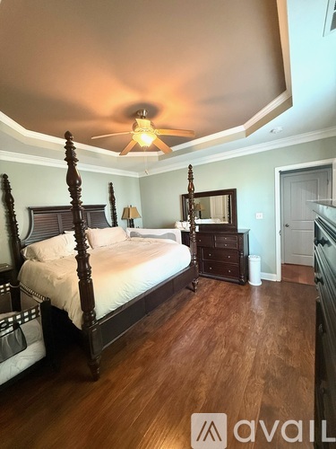 A bedroom with a large bed and wooden floors.