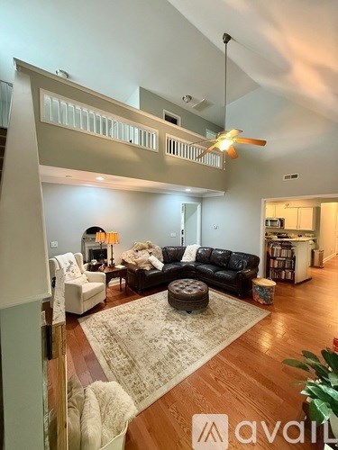 A living room with a black couch and a rug.