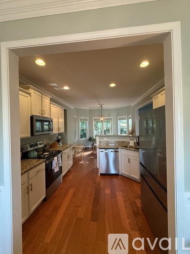 A kitchen with white cabinets and a wooden floor.