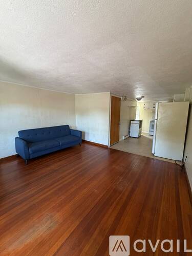 A room with a blue couch and wooden floors.