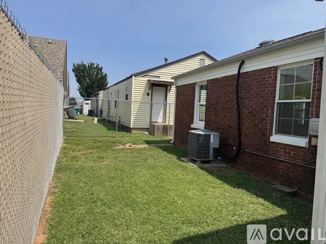 A chain link fence separates a grassy area from a row of houses.