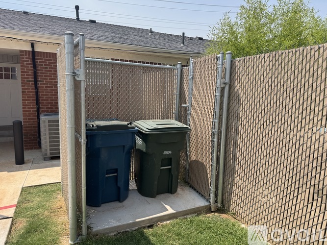 A fenced area with two trash bins.