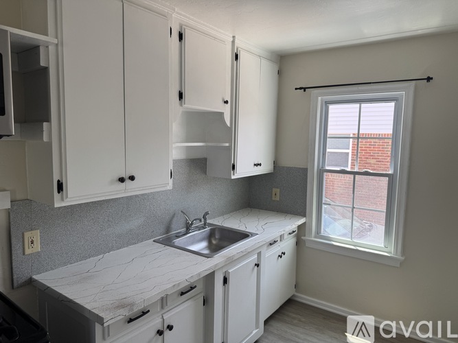 A kitchen with white cabinets and a marble countertop.