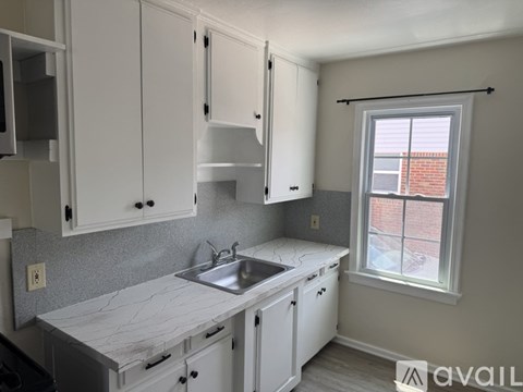 A kitchen with white cabinets and a marble countertop.