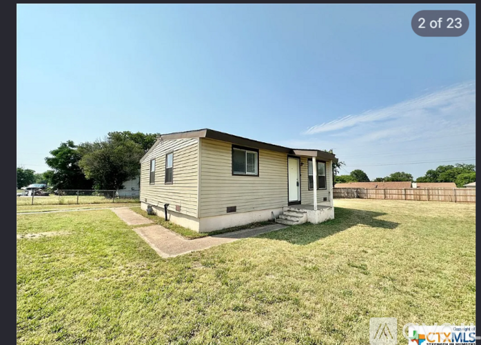 A small house with a fence in the background.