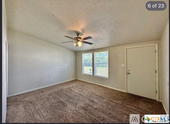 A room with a ceiling fan and carpeted floor.