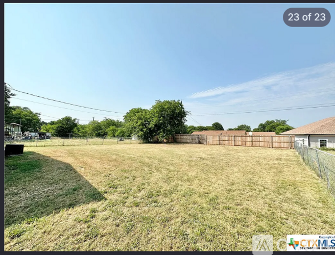 A field with a fence and a building in the background.