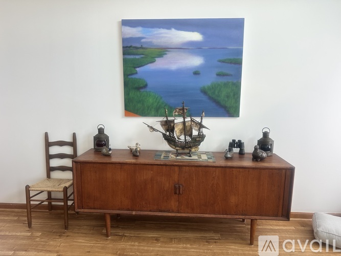 A wooden cabinet with a painting on the wall behind it.