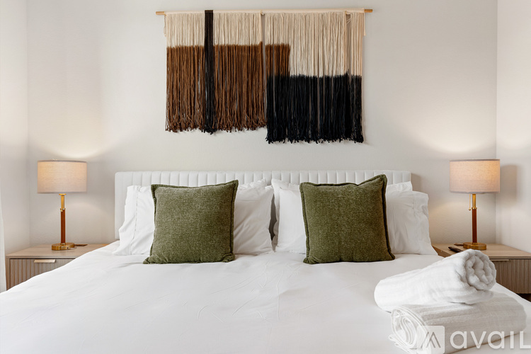 A bedroom with a white bed and two green pillows.