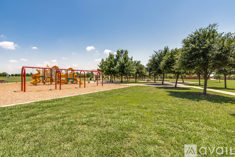 A playground with a red swing set and a green lawn.
