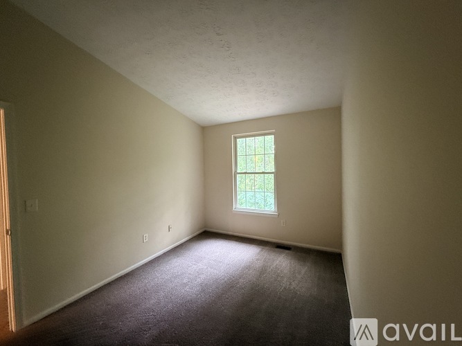 Empty room with a window and carpeted floor.