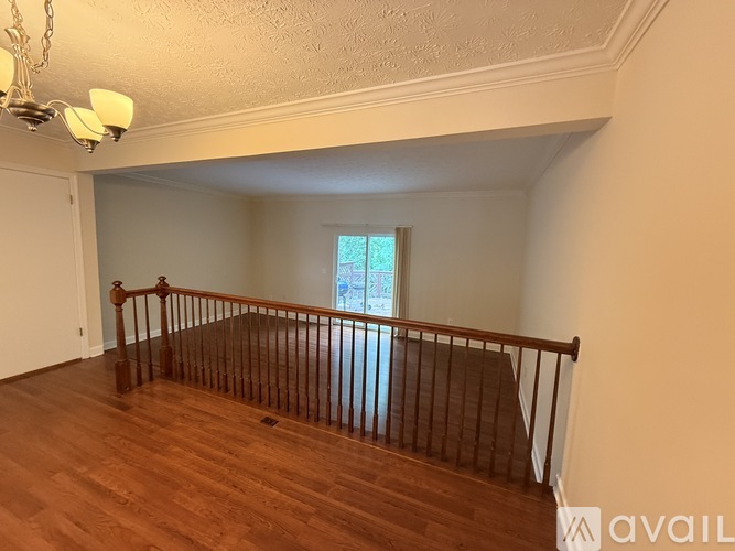 A room with wooden floors and a window with a view of trees.