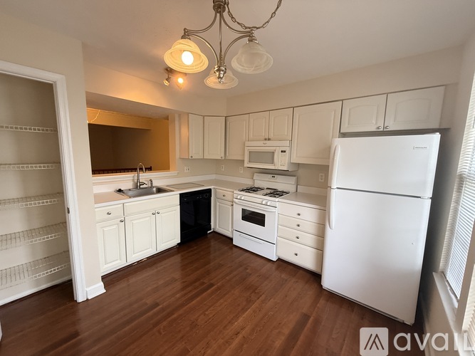 A kitchen with white appliances and wooden floors.