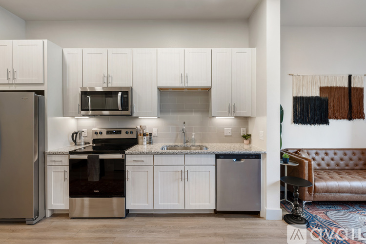 A modern kitchen with white cabinets and stainless steel appliances.