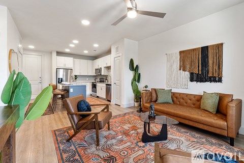 A living room with a brown couch and a rug with a pattern on it.