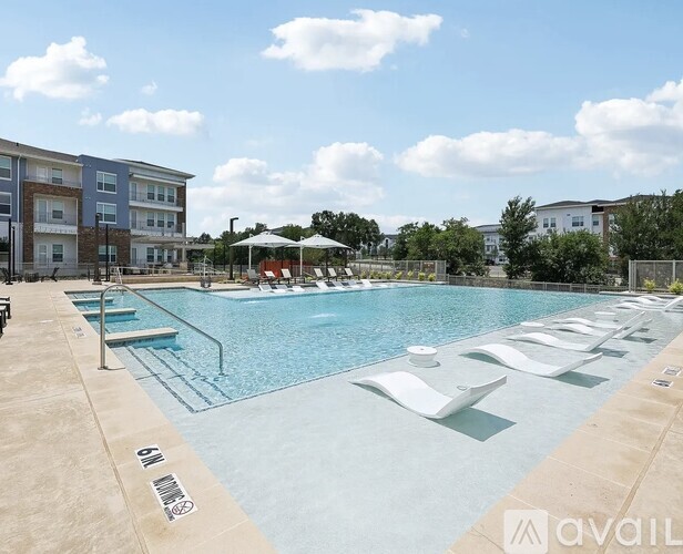 A large outdoor swimming pool with lounge chairs and a building in the background.