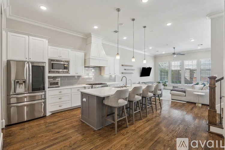 A modern kitchen with wooden floors and stainless steel appliances.