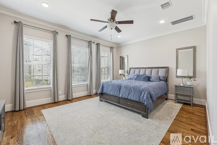 A bedroom with a large bed and a ceiling fan.