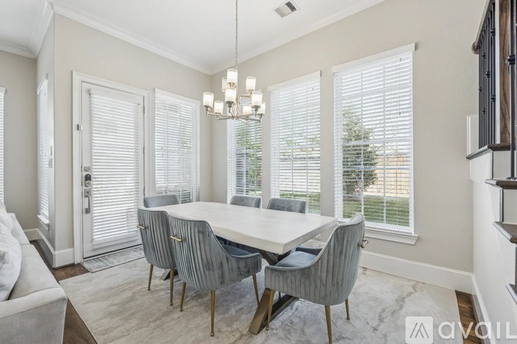 A dining room with a white table and grey chairs.