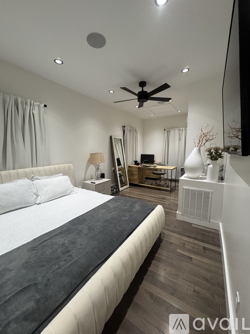 A bedroom with a large bed and a ceiling fan.