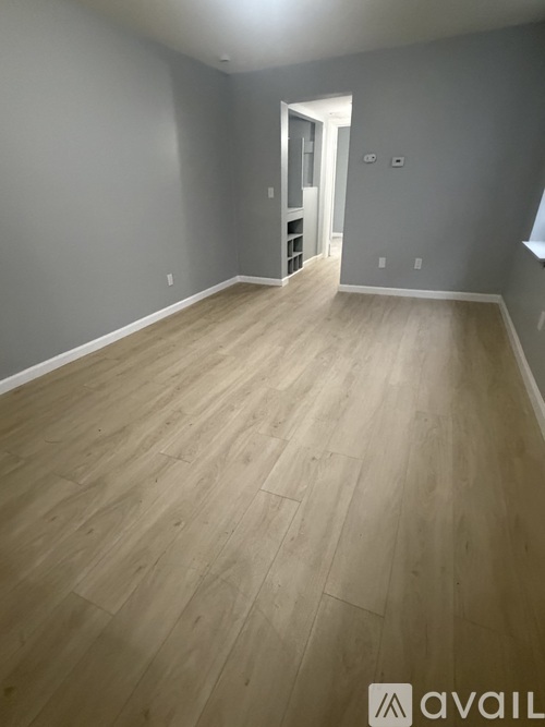 A room with wooden flooring and a doorway leading to another room.