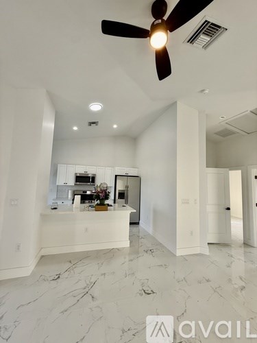 A spacious kitchen with white cabinets and marble flooring.